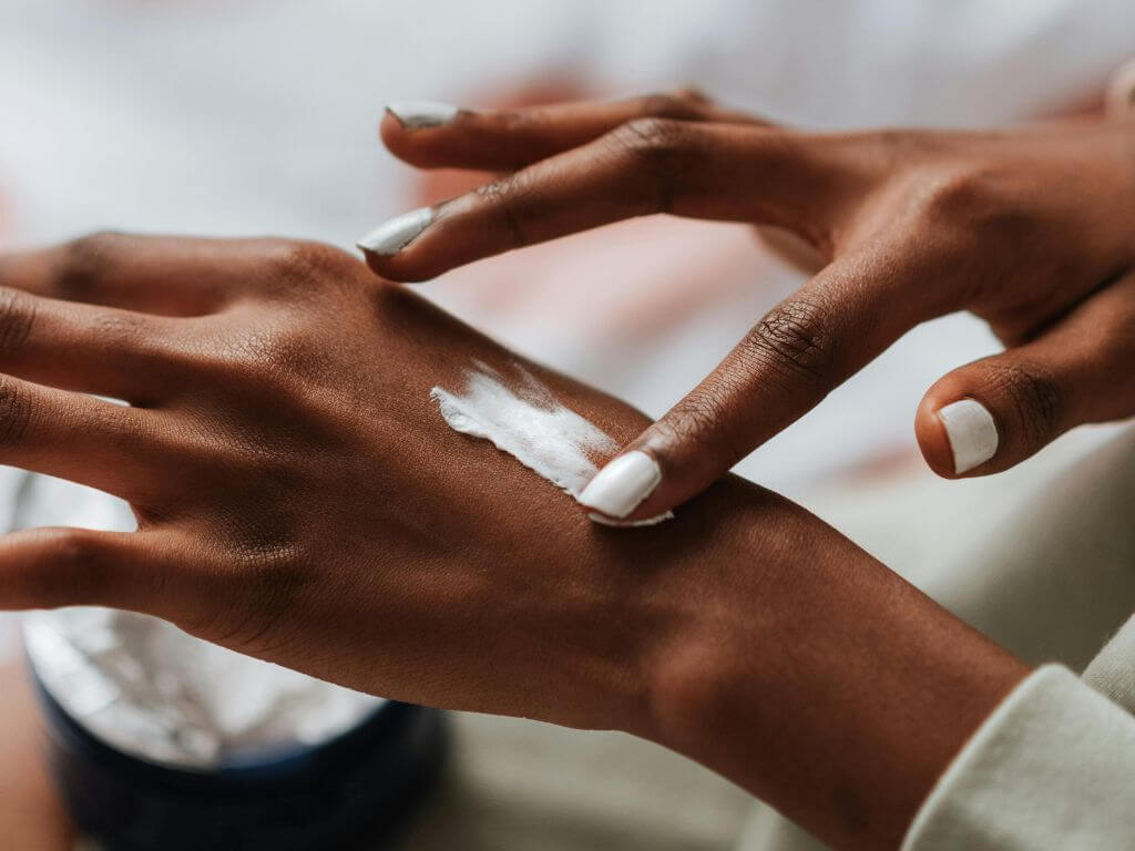 A woman applying hand cream, gently rubbing it into her skin.